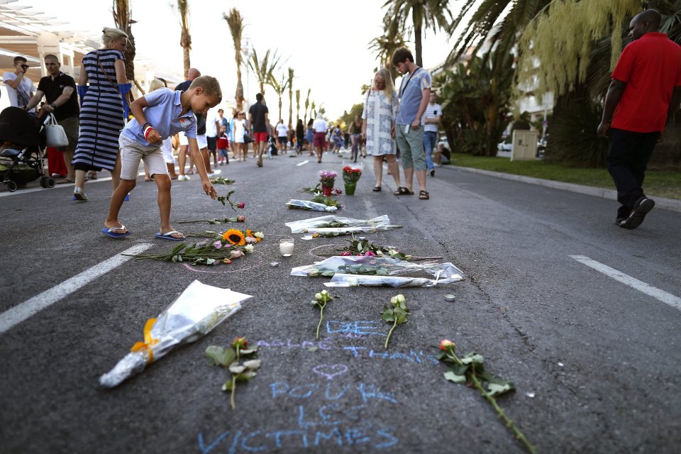 Children place flowers at the scene where more than 80 people lost their lives