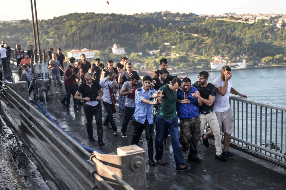  People apprehend a Turkish soldier (third right in blue) that participated in the attempted coup, on Istanbul's Bosporus Bridge