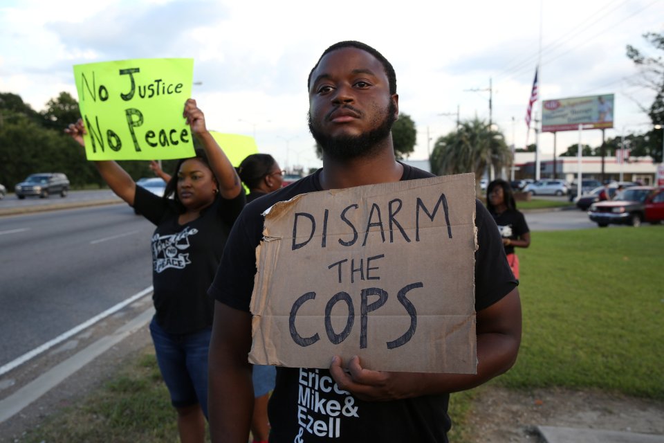  Activist Matthew Kincaid holds a sign that reads 'Disarm the cops' as he protests Sterling's killing in Baton Rouge, Louisiana