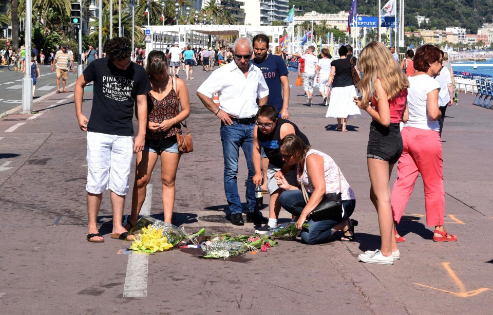  A small crowd gathers to pay tribute to a person who lost their life during Bastille Day celebrations last week when a terrorist attacked