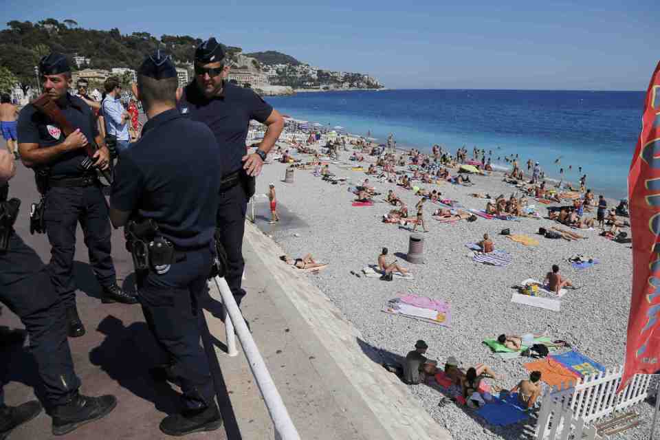  French CRS police patrol on the walkway above a public beach with sunbathers as security measures continue