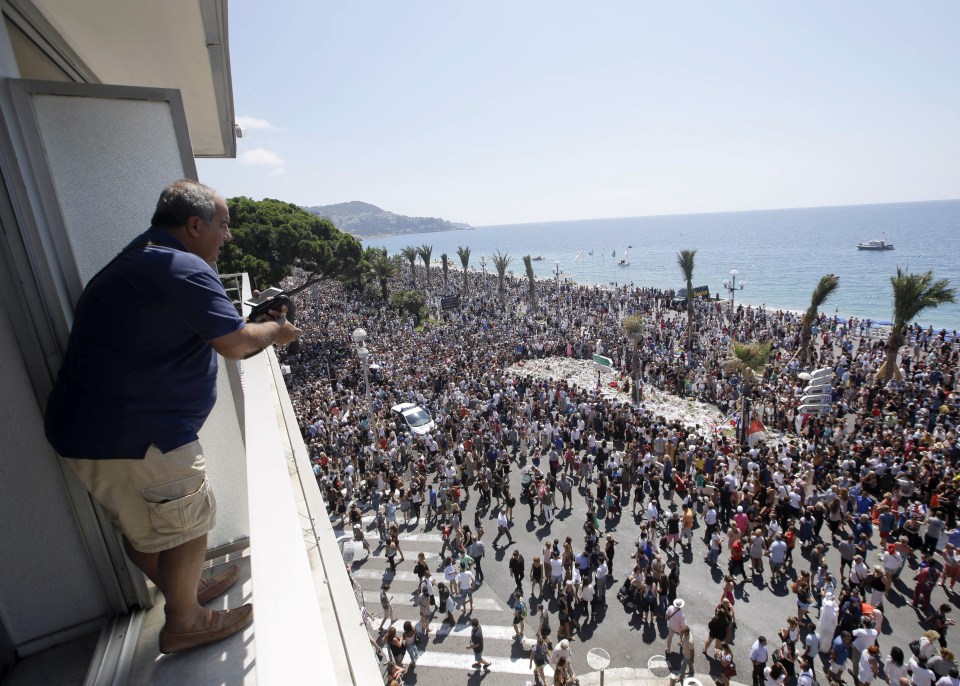  Ghassan Zaour watches people gathered around a makeshift memorial after observing a minute of silence to honor the victims of deadly attack in Nice