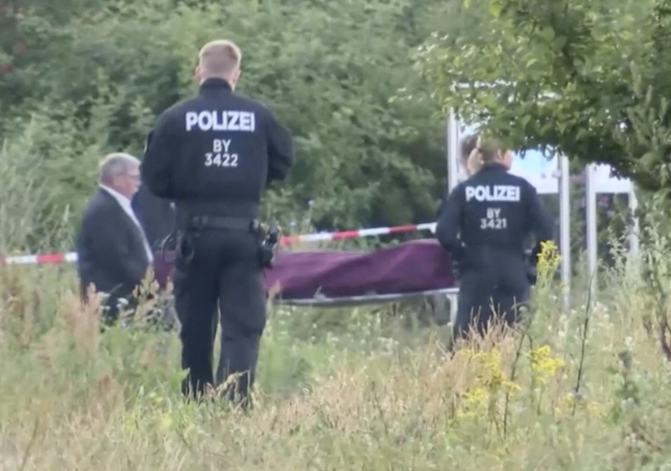  The body of the Wurzburg attacker is carried away by police after he was shot dead for knifing four commuters