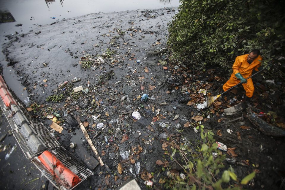  A man helps clean the Meirti river that flows into Guanabara Bay, where the sailing competitions will be held during the upcoming Rio Games