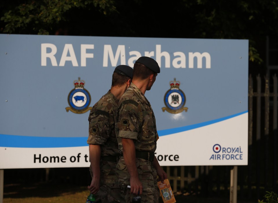 Servicemen walk past a sign at the entra