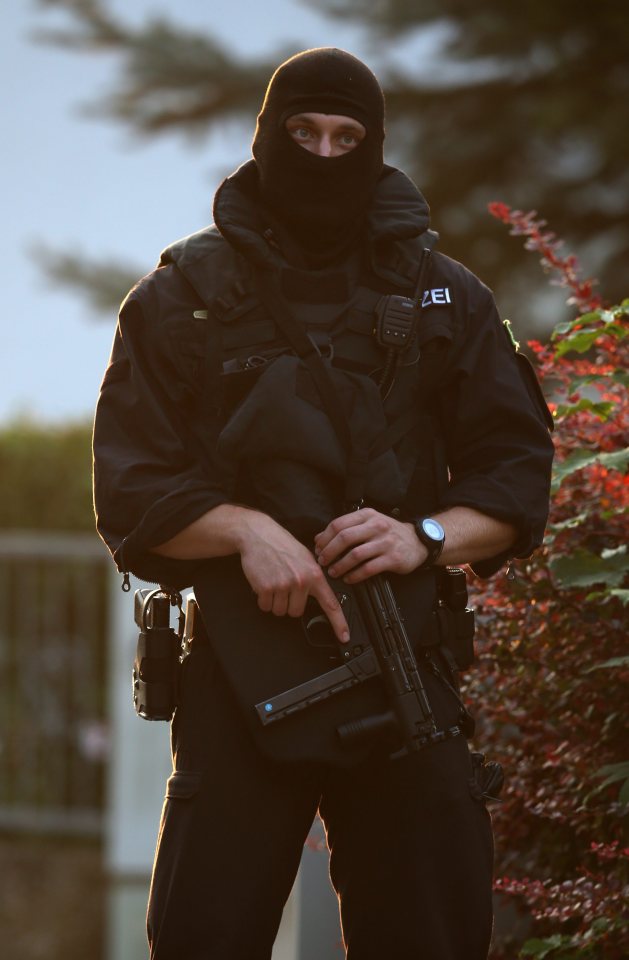  A heavily armed police officer stands guard at the crime scene