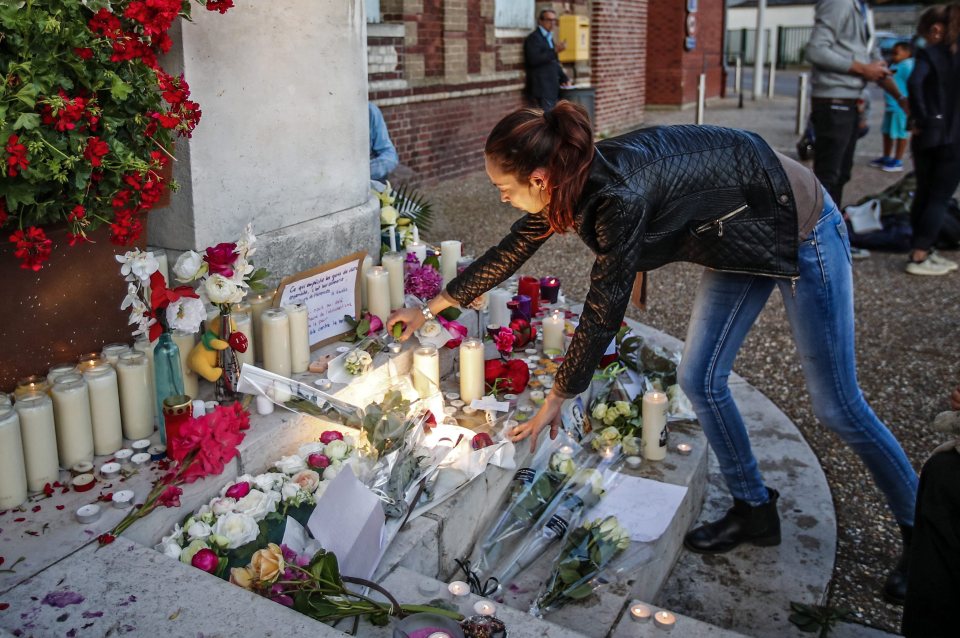  A woman lights candle at a makeshift memorial in front of the city hall in Saint-Etienne-du-Rouvray