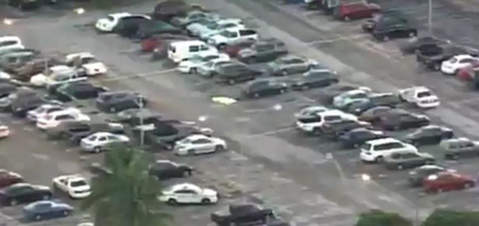  Aerial footage shows the crime scene featuring a corpse covered with a tarp in the middle of the car park