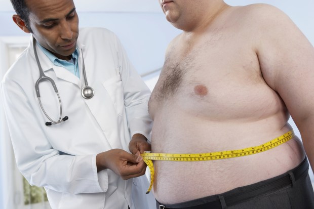 General practioner measuring the waist of an obese patient