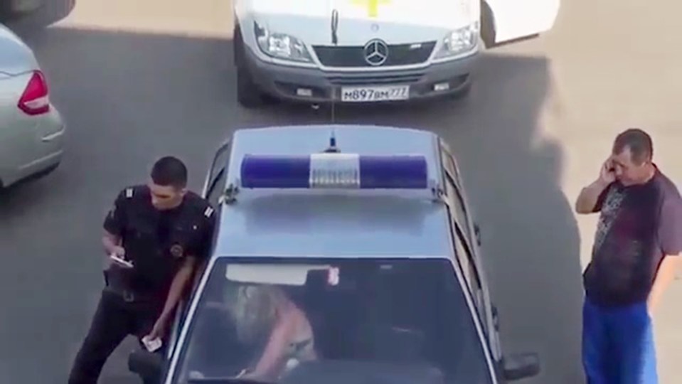  The bikini-clad woman is first seen handcuffed inside the police patrol car