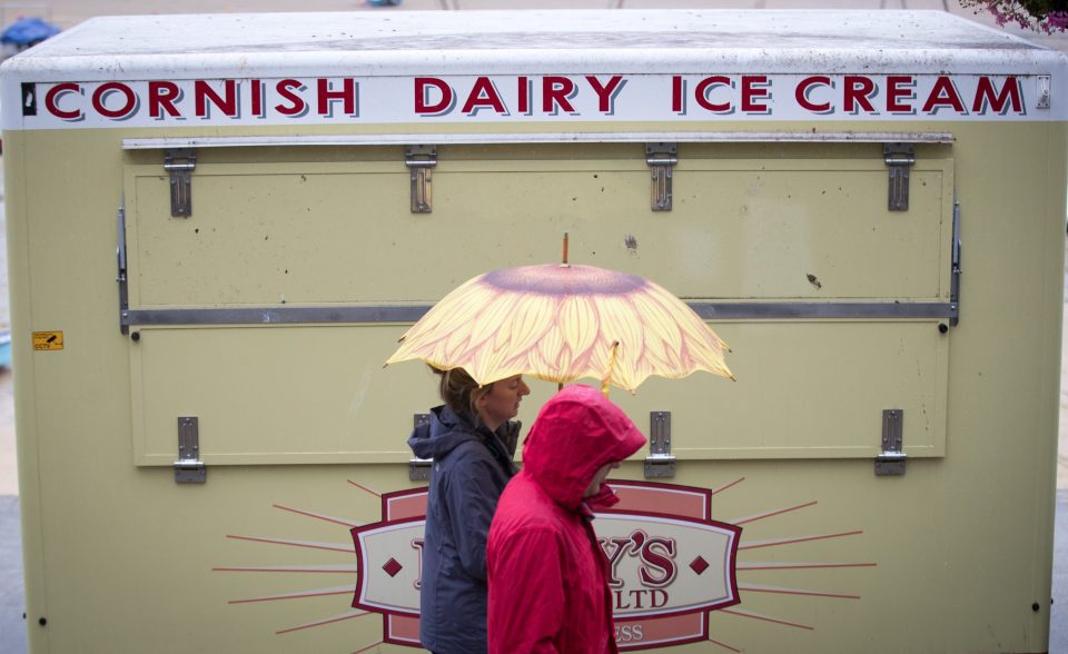  A couple pass a closed ice cream seller's booth besides the harbour in St Ives on the first day of August