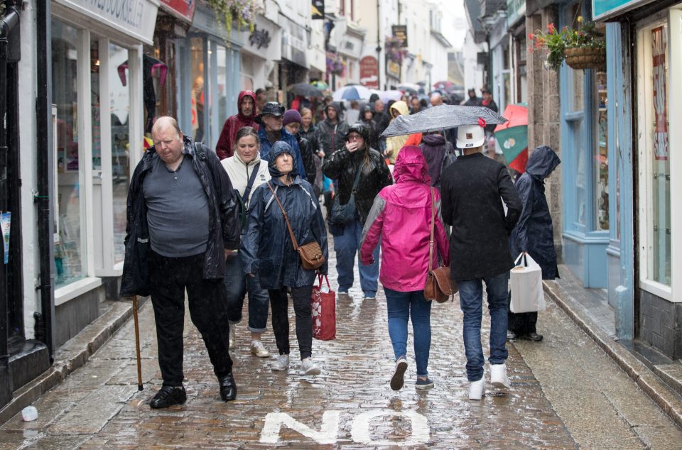 In St Ives people braved the showers to visit the towns shops - with the weather looking more wet and wintry than summery