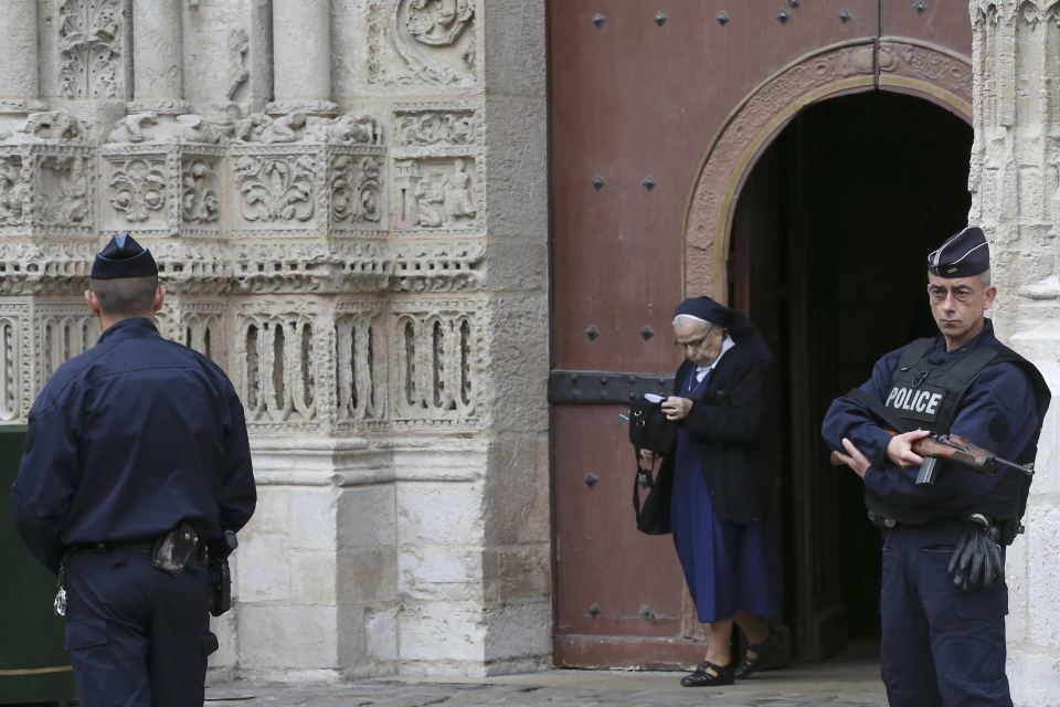 Armed French police stand guard as a nun leaves the Cathedral in Rouen after a funeral service in memory of slain French parish priest Father Jacques Hamel in Rouen