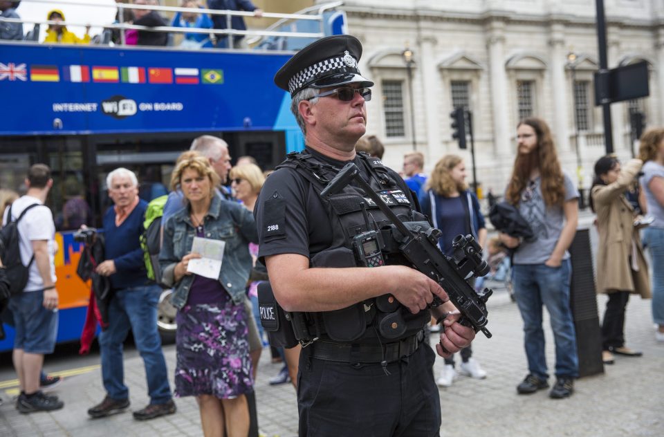  A cop stands on Whitehall in the City of Westminster as an open top tour bus goes by