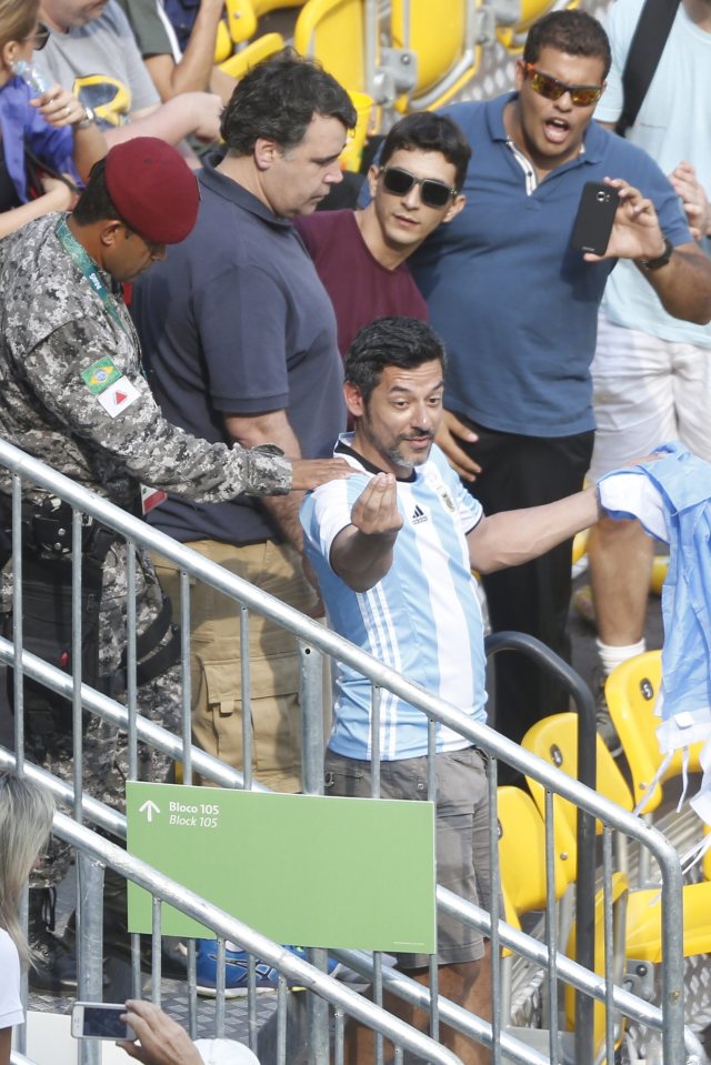 The enraged fan gestures towards his Brazilian counterpart as he is removed from the court