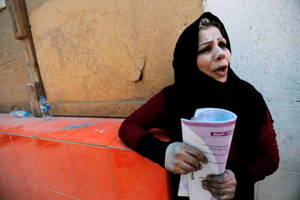  An Iraqi woman with blackened hands waits outside the charred hospital