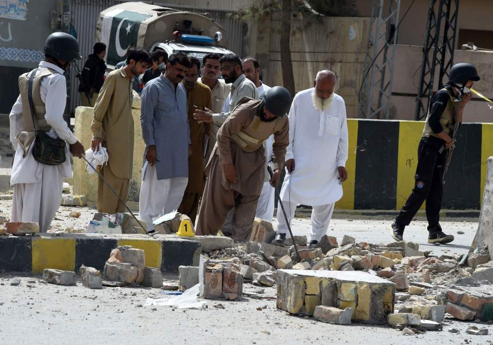  Pakistani security officials inspect the site of a roadside bomb blast