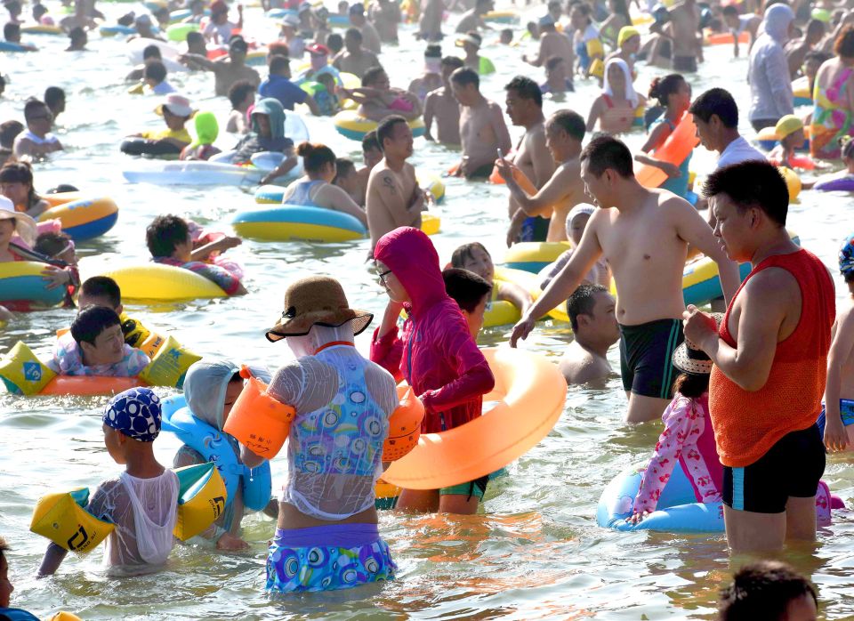  Beachgoers used the water to cool off while also keeping their t-shirts and jumpers on to shade themselves from the sun