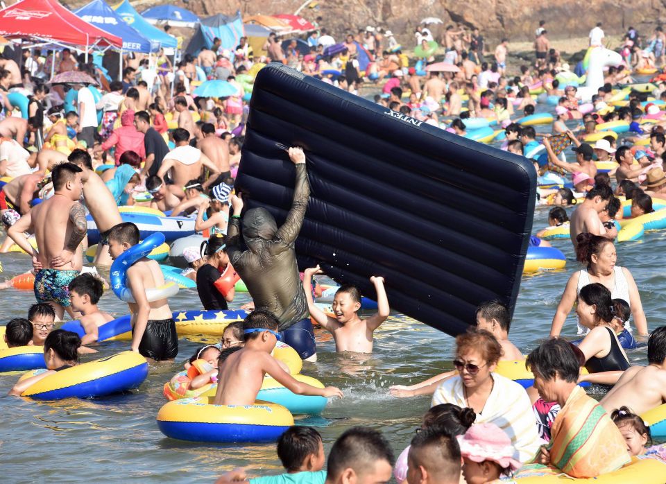  A man vying with huge crowds tries to position his lilo in the water