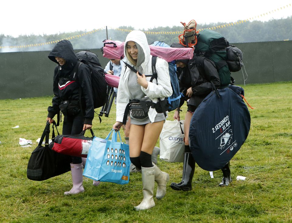  Revellers covered themselves from the rain in ponchos as they carried their camping gear