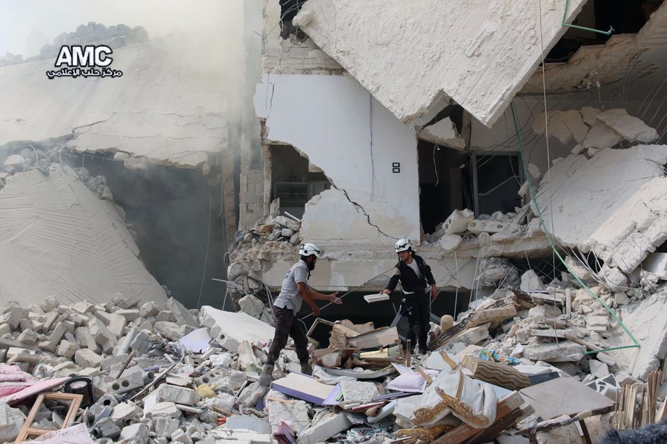  Workers inspect damaged buildings after barrel bombs were dropped on Aleppo