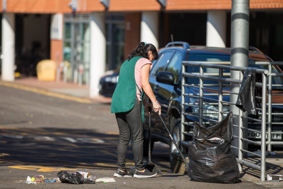  A woman sweeps up the mess left on the street