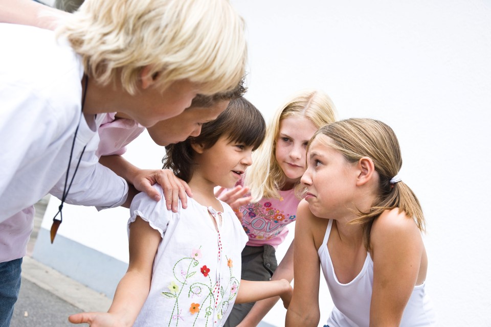 Young schoolgirl in the schoolyard, talking with older children