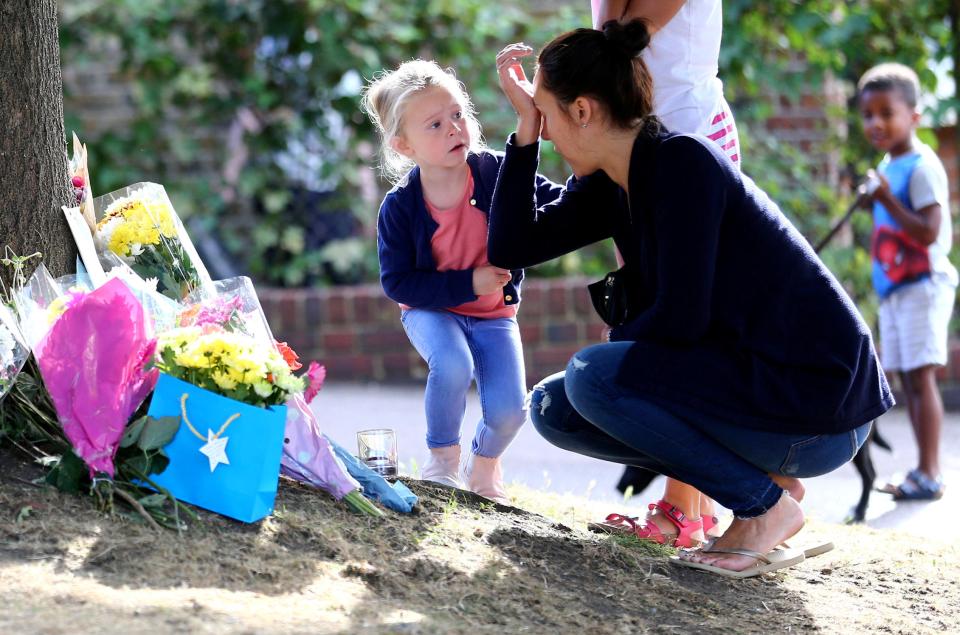  A woman is comforted by a child as she lays flowers at the scene in Penge where a little boy and his aunt were killed