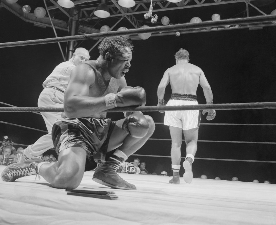 (Original Caption) The Knees Buckled Under Old Arch. New York, New York: Rocky Marciano backs away from the floored Archie Moore in the ninth and final round of their title bout at the stadium tonight. The knees literally buckled under the game challenger after he absorbed a flurry of lefts and rights. He is down for the count. Time was 1:19.