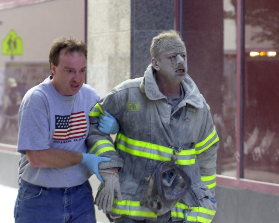 A soot-covered fireman is helped away from the Twin Towers