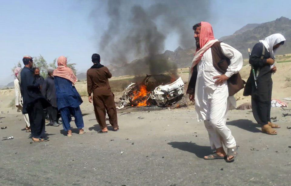  Locals stand next to a flaming car destroyed in a US drone strike in northern Pakistan