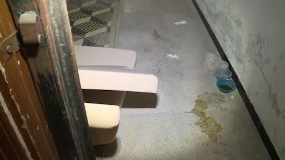  Plastic bowls containing powder and liquid lie on the filthy floor of a cell