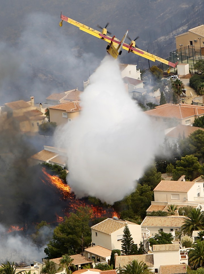  A plane battling the blaze yesterday drops water over Benitachel village