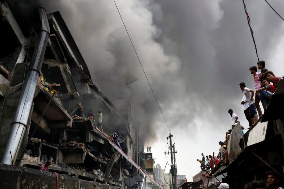  People look on as thick smoke pours from the building which was destroyed by a huge fire this morning