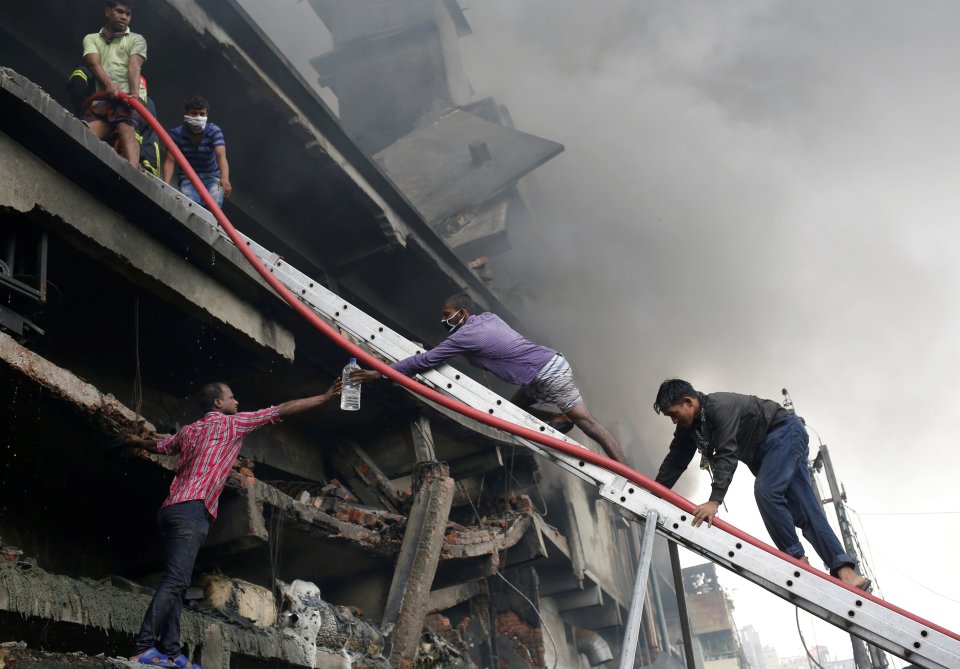  People try to help the firefighters to extinguish a fire at a garment packaging factory outside Dhaka