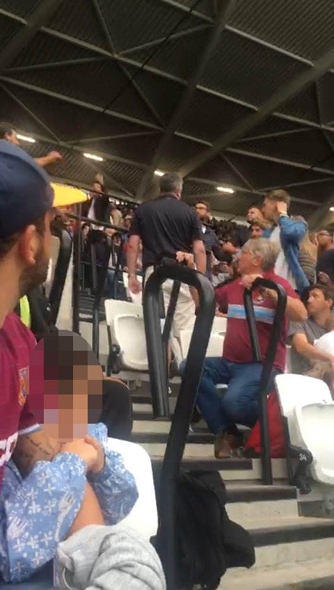  The child clutches her dad's arm in terror as the fans brawl in the rows behind