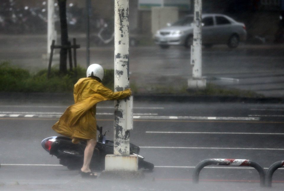  A motorist holds on to a post as she braves high winds and rain of Super Typhoon Meranti in Kaohsiung, southern Taiwan