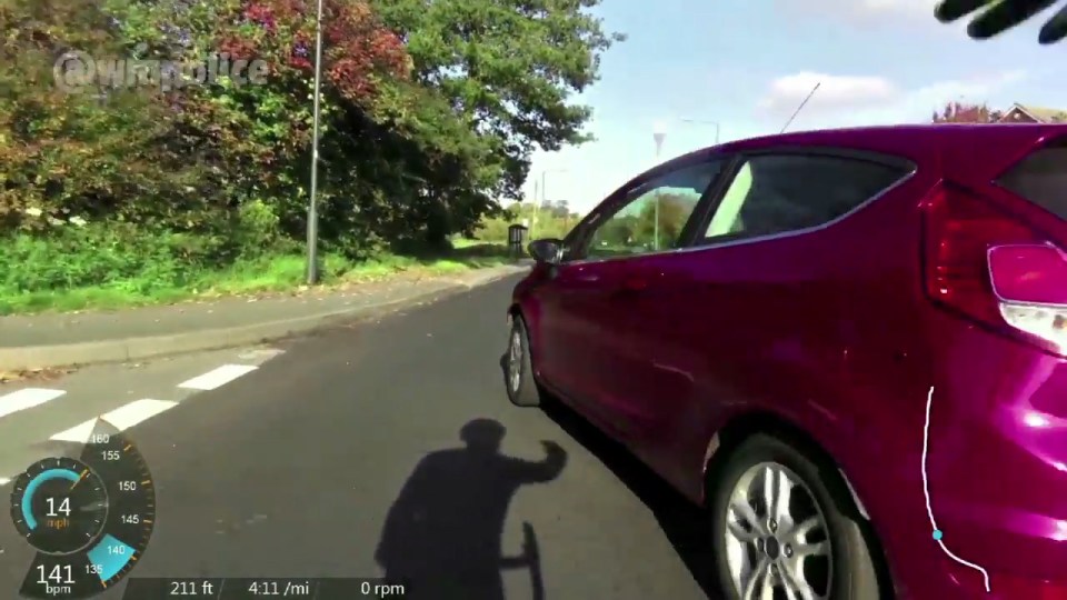  Shadow on road shows cyclist raising his fist in objection as driver pulls out from a junction into their path