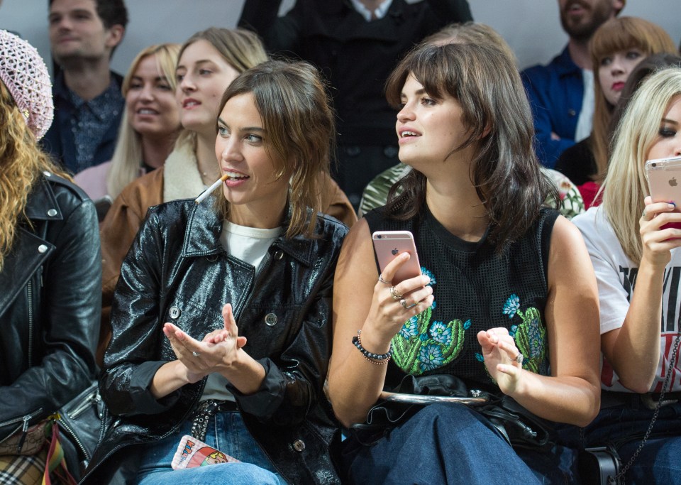  Alexa Chung holds a cigarette between her teeth as she enjoys thew House of Holland show with Pixie Geldof