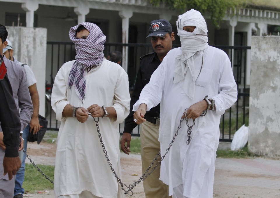  A police officer escorts father Muhammad Shahid, right, and ex-husband Muhammad Shakeel to court