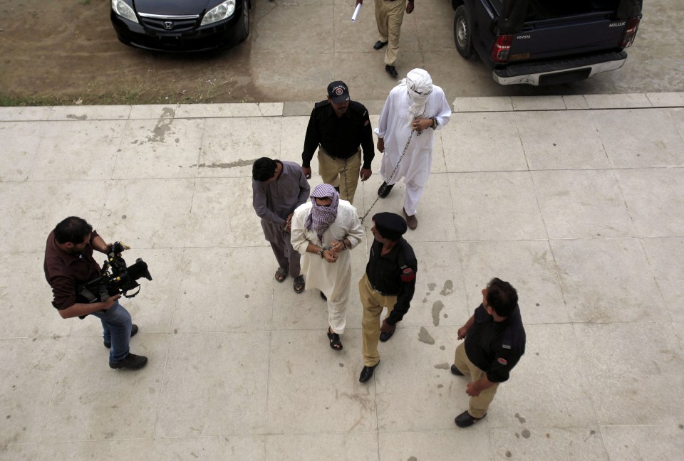  The accused enter court surrounded by armed cops