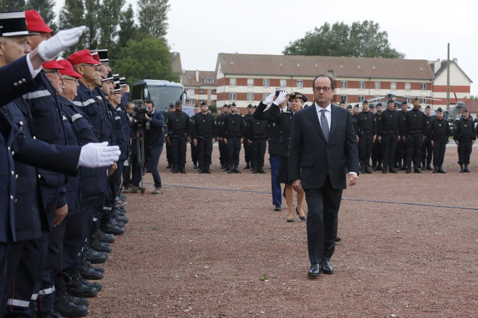  Hollande, seen striding through an inspection with officers, has vowed to close the Calais Jungle