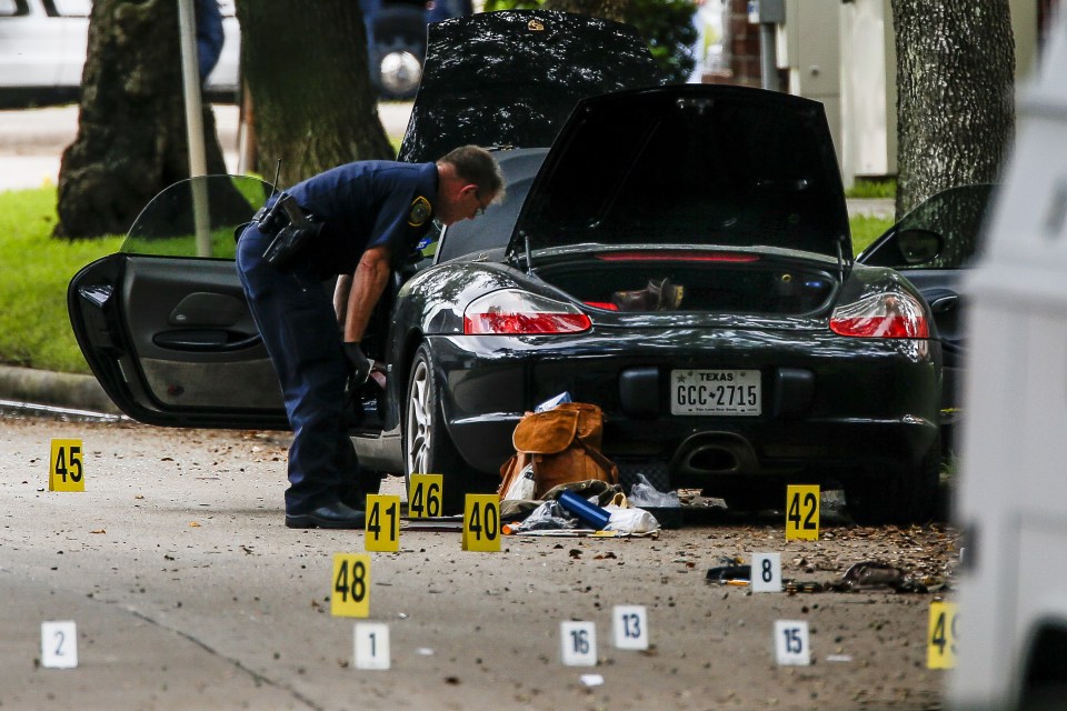  A police officer investigates a car belonging to local lawyer who shot and injured multiple people before he was killed