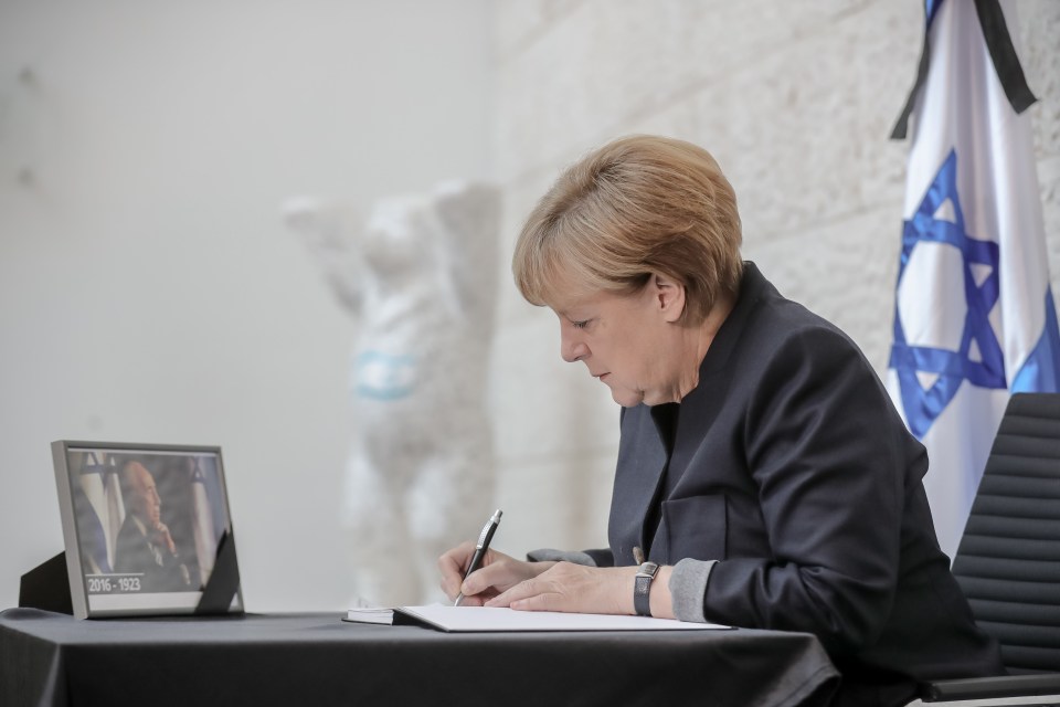  German Chancellor Angela Merkel was pictured signing a book of condolence for Peres' family today