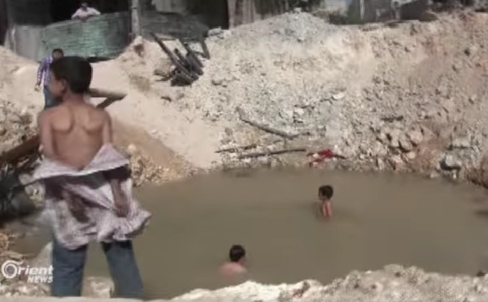  Children swim in a crater which was made by a bomb in Aleppo, Syria