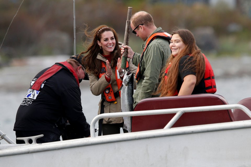 Britain's Prince William holds a fish as Kate, Duchess of Cambridge, looks on while fishing during a visit to Haida Gwaii in Skidegate