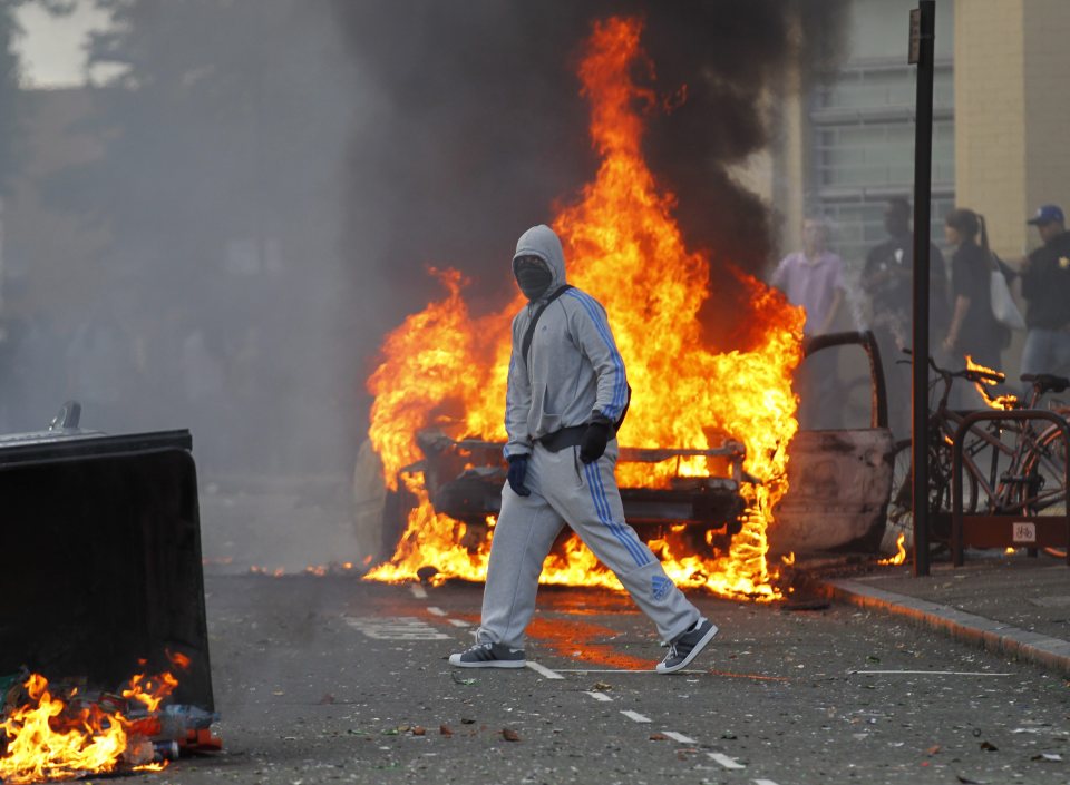  Blaze . . . young man walks in front of burning car during London's 2011 riots