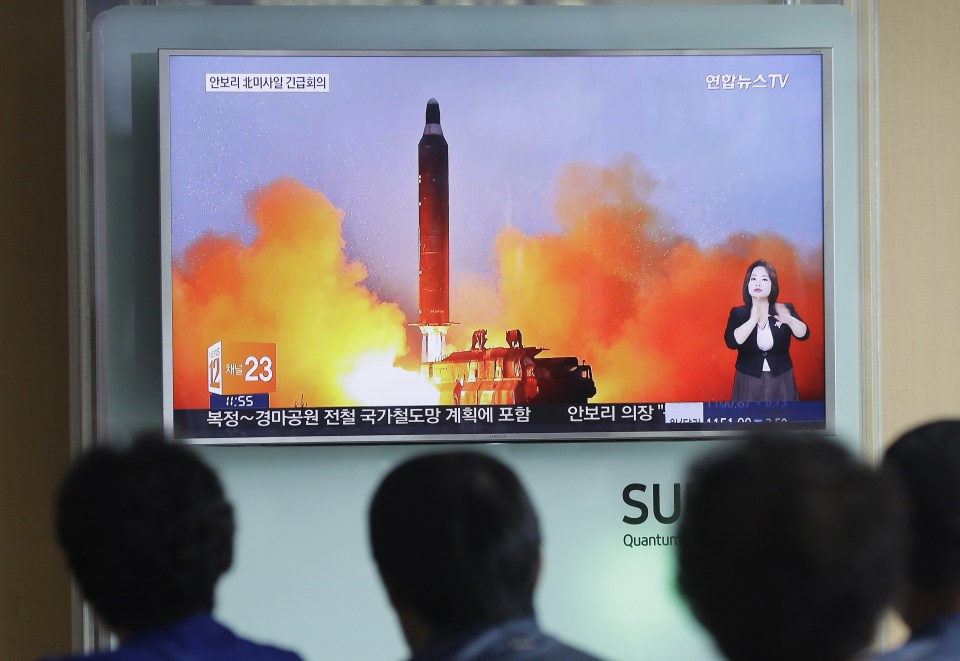  People watch a TV news channel airing an image of a North Korean ballistic missile launch