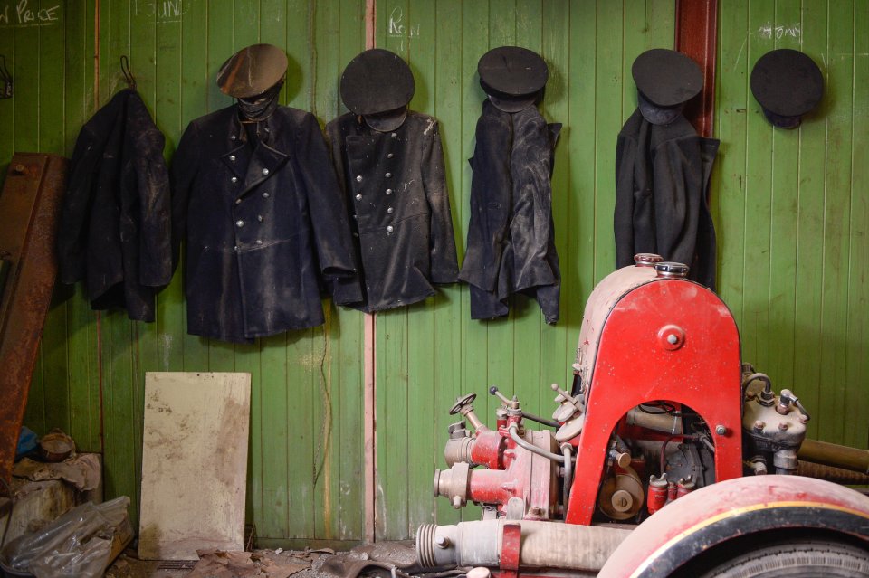  Jackets and caps hang on pegs with names including I Silk, W Price and A Round scrawled above them in chalk