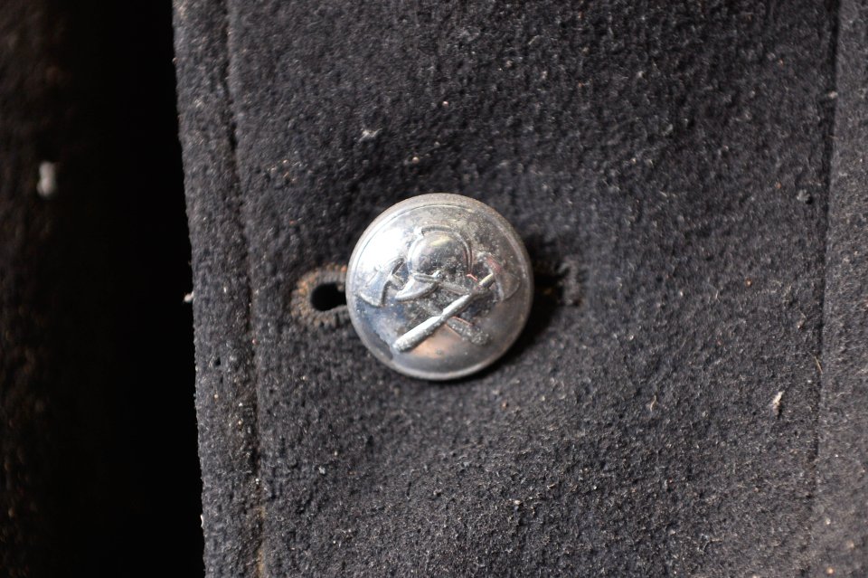  The shiny button on a firefighter's jacket shows a helmet and two axes